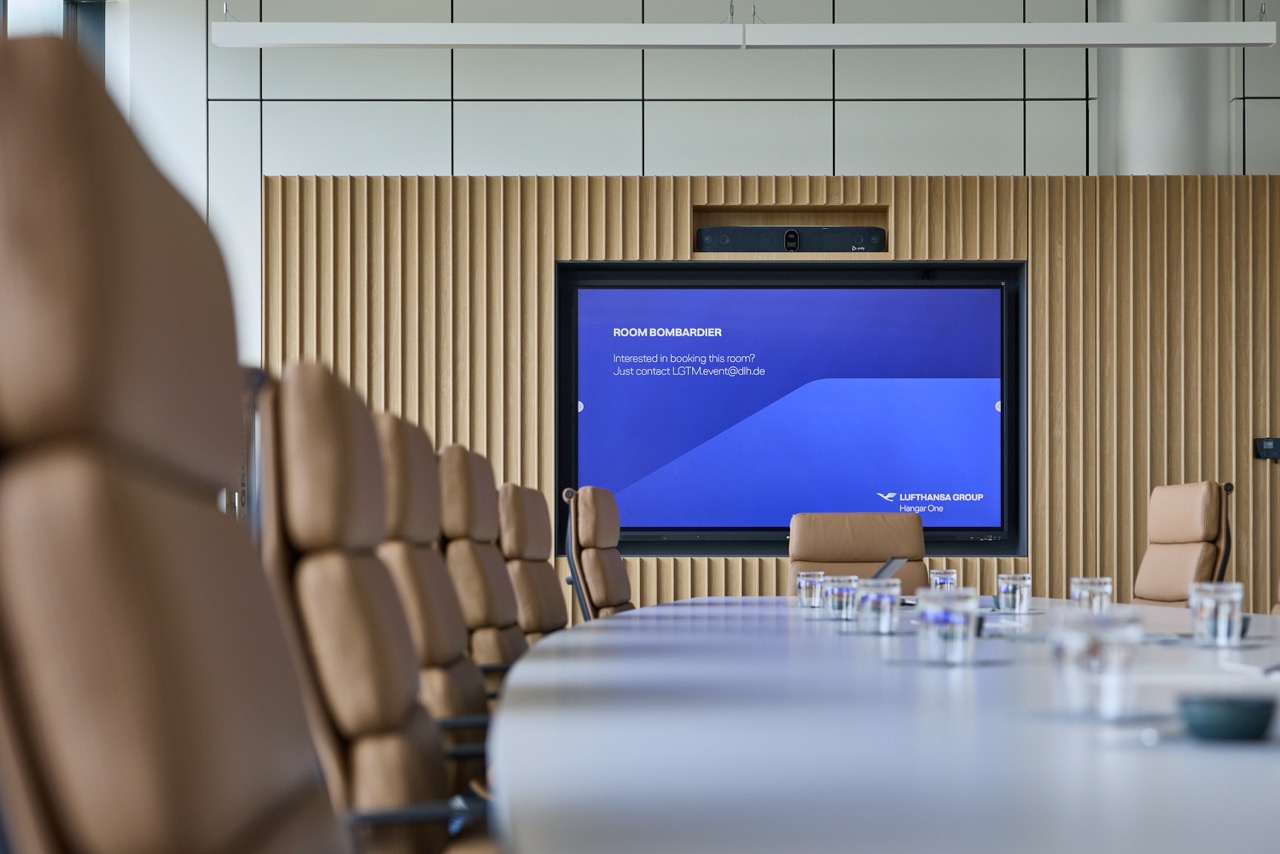 Conference room with a meeting table, leather chairs, and a large screen at the front