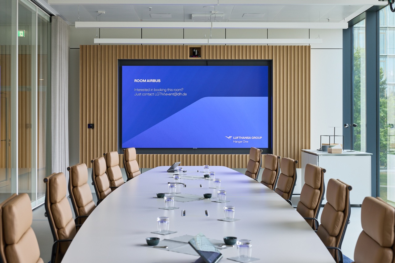 Conference room with a meeting table, leather chairs, and a large screen at the front